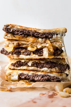 a patty melt stacked made with sourdough bread, caramelized onions, swiss cheese and mayo