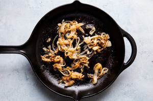 thinly sliced onions caramelizing in a cast iron skillet