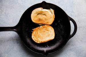 two toasted patty melt sandwiches in a pan made with caramelized onions and Swiss cheese in a cast iron skillet