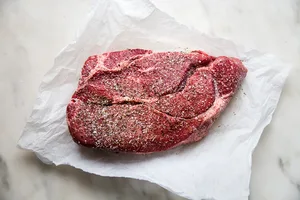 Chuck roast on parchment paper seasoned with salt and pepper