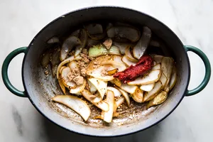 Onion slices with tomato paste, brown sugar and herbs shown in a large dutch oven