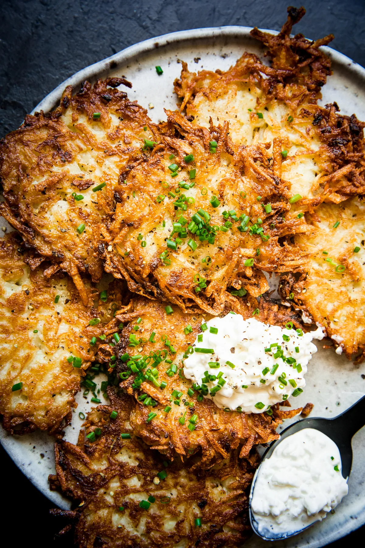 homemade potato pancakes on a plate topped with a dollop of sour cream in a of the best breakfast potato dish recipes