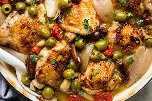 chicken Provençal with green and black olives, tomatoes, shallots, and white wine in a large braising pot