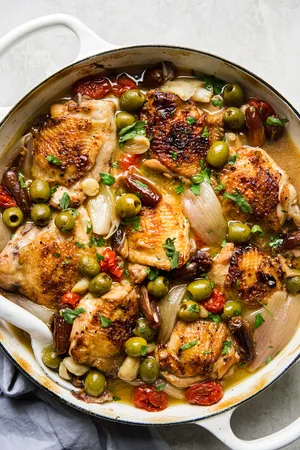 chicken Provençal with green and black olives, tomatoes, shallots, and white wine in a large braising pot