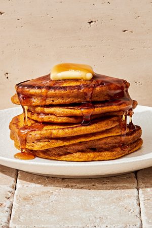 stack of homemade pumpkin pancakes topped with butter and dripping with maple syrup in a list of the best breakfast ideas