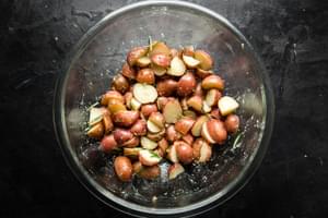 boiled potatoes in a bowl tossed with olive oil, garlic powder and rosemary