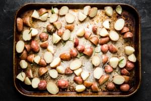 boiled potatoes on a baking sheet tossed with olive oil, salt, garlic powder and rosemary