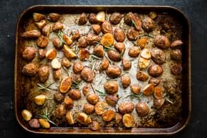 roasted potatoes on a baking sheet tossed with olive oil, salt, garlic powder and rosemary