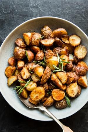 boiled potatoes in a bowl with olive oil, salt, garlic powder and rosemary