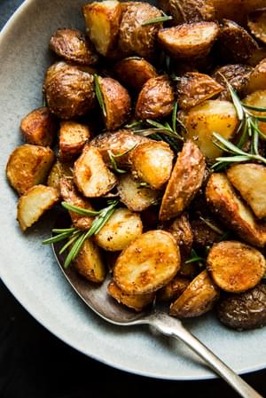 boiled potatoes in a bowl with olive oil, salt, garlic powder and rosemary