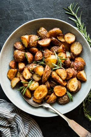 boiled potatoes in a bowl with olive oil, salt, garlic powder and rosemary