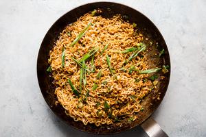 Sesame Garlic Ramen Noodles in a pan with green onions and stir fry sauce.