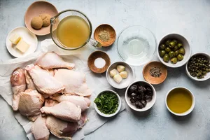 raw chicken on parchment, parsley, green olives, capers, brown sugar, butter, garlic, salt, pepper, chicken