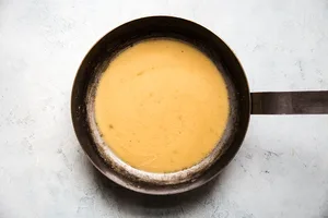 the pan juices from the sheet pan chicken marbella in a sauce pan with butter