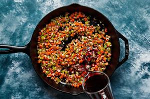 celery, diced carrots, and onion being cooked in a cast iron skillet