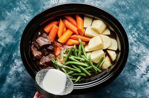 corn starch slurry, green beans and carrots being added to slow cooker beef stew.