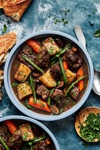 a bowl of slow cooker beef stew made with potatoes, green beans, carrots, onions and celery