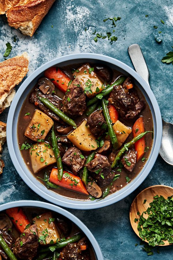 a bowl of slow cooker beef stew made with potatoes, green beans, carrots, onions and celery