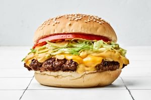 smash burger on a toasted bun, layered with crisp lettuce, cooked onion, melted American cheese, and a slice of fresh tomato