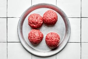 Four raw ground beef balls, prepped and ready to be smashed into burgers