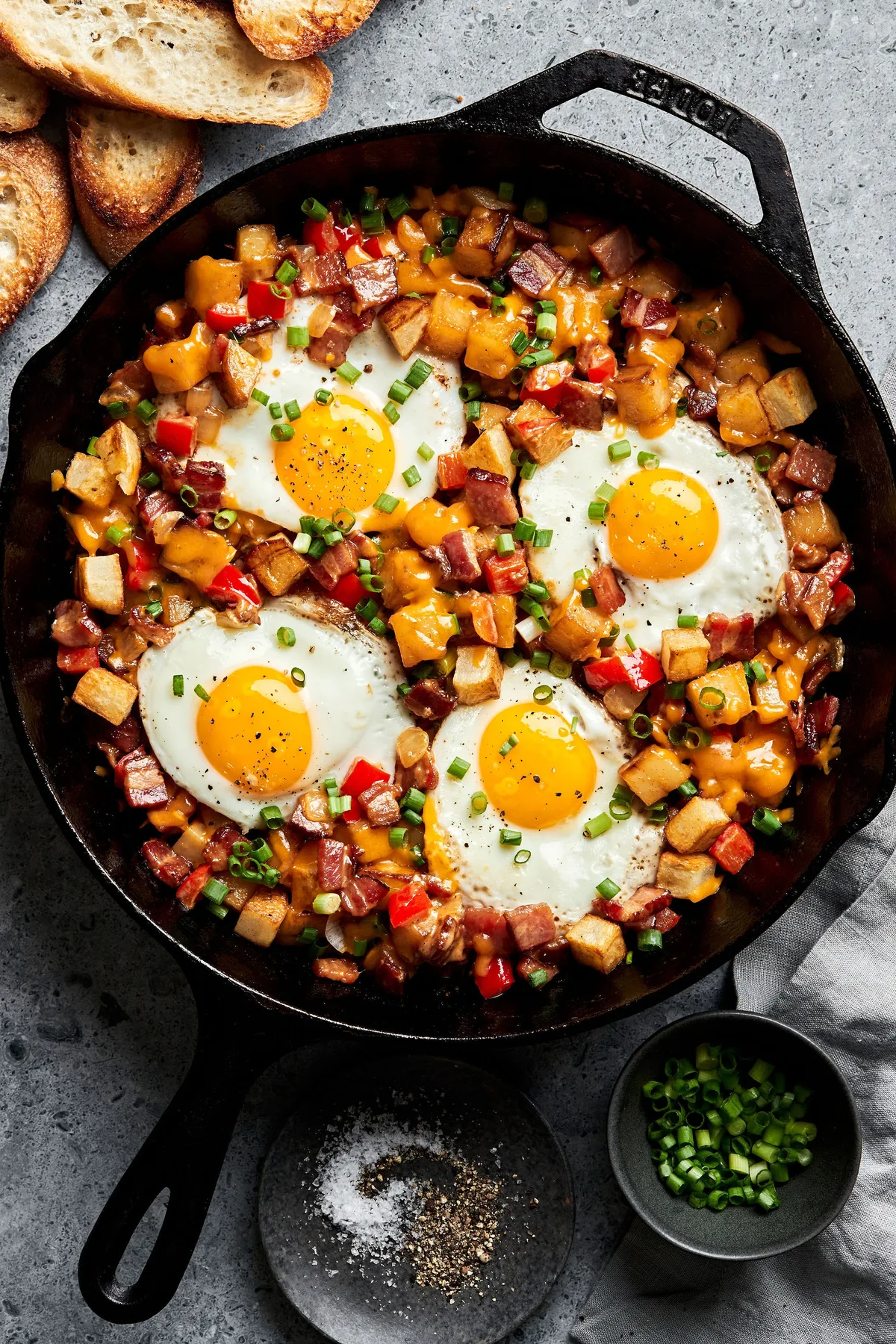 Homemade smoky bacon cheddar breakfast hash in a skillet topped with fried eggs in a list of the best breakfast recipes