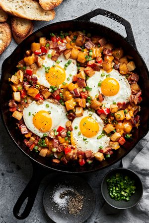 Homemade smoky bacon cheddar breakfast hash in a skillet topped with fried eggs in a list of the best breakfast recipes