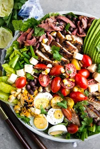 southwest cobb salad with bacon, chipotle dressing, avocado, corn and beans in a bowl
