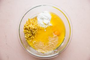flour, cornmeal, sugar, baking powder, salt, butter, eggs, creamed corn, whole corn, and sour cream in a glass bowl