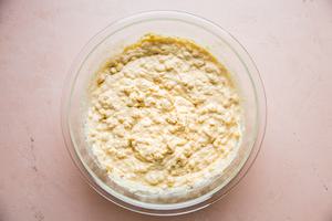 spoon bread batter in a glass bowl made with flour, cornmeal, sugar, baking powder, salt, butter, eggs, corn & sour cream