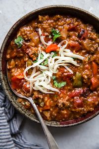 Stuffed pepper soup with ground beef, cilantro, shredded cheese in a bowl