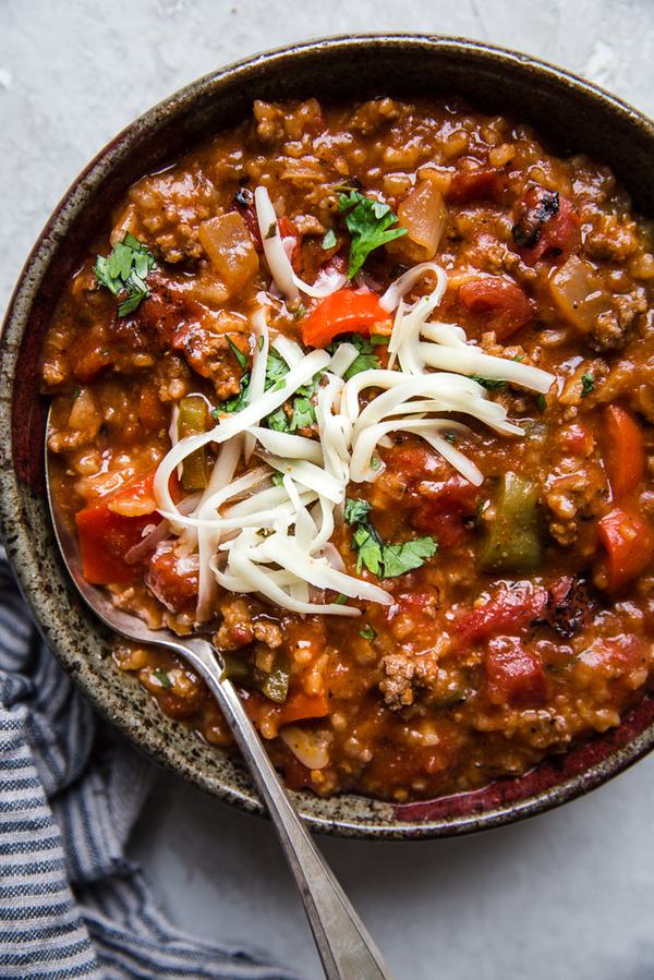 Stuffed pepper soup with ground beef, cilantro, shredded cheese in a bowl