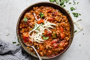 homemade stuffed pepper soup in a soup pot with tomatoes, rice, bell peppers, onion, taco seasoning with shredded cheese