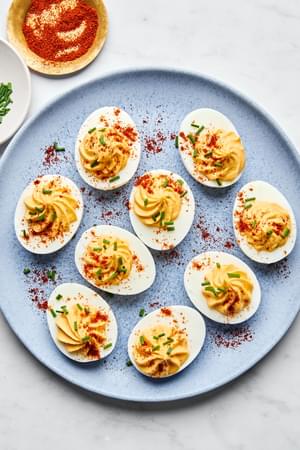 a plate of homemade deviled eggs sprinkled with paprika and chives
