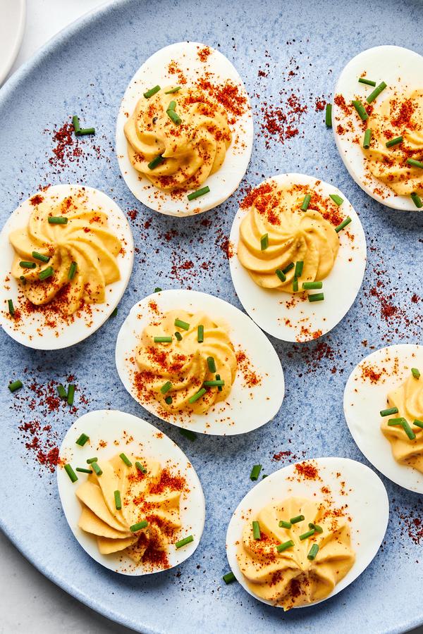 a plate of homemade deviled eggs sprinkled with paprika and chives