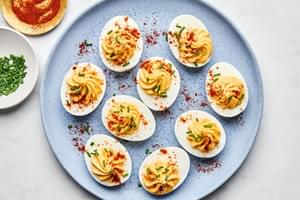 a plate of homemade deviled eggs sprinkled with paprika and chives