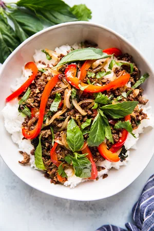 thai basil beef over white rice in a large white bowl
