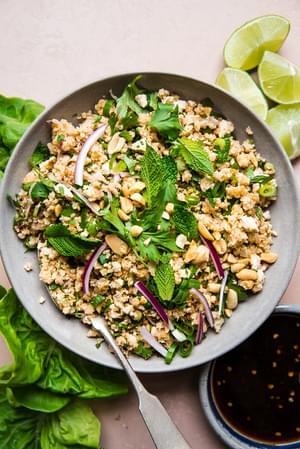crumbled tofu for lettuce wraps shown in a large bowl along with homemade sauce, lime wedges and lettuce leaves