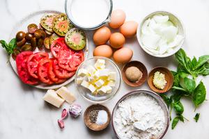 Tomato slices, fresh basil, sweet onion slices, garlic, butter, flour, eggs and heavy cream in small bowls and plates