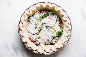 raw pie crust filled with sliced caramelized onions, sliced tomatoes and topped with parmesan cheese and fresh basil