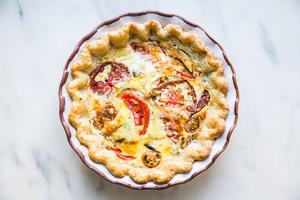 Tomato, basil and caramelized onion quiche in a ceramic pie dish