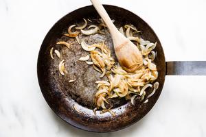 yellow onions caramelized in a skillet with a wooden spoon