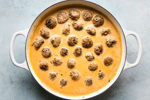 turkey meatballs in a red curry sauce in a large white skillet