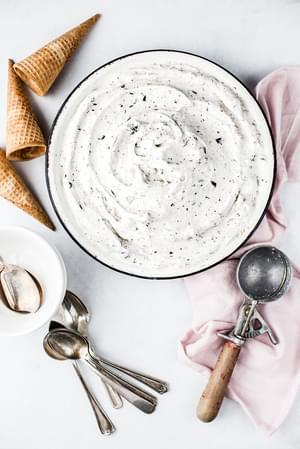 Vegan Mint Chip Ice Cream in a pie tin next to ice cream cones and an ice cream scooper