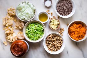dried past, bowl of walnuts, bowl of lentils, garlic, shredded carrots, olive oil celery, onion and marinara