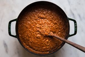 vegan walnut and lentil bolognese in a dutch oven with a wooden spoon