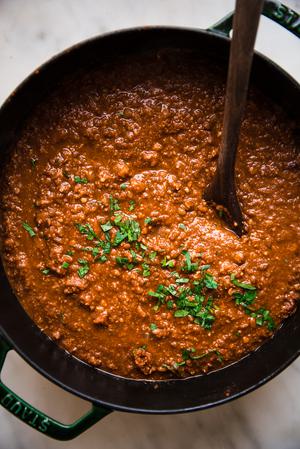 vegan walnut and lentil bolognese in a dutch oven with a wooden spoon