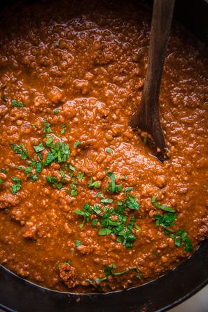 vegan walnut and lentil bolognese in a dutch oven with a wooden spoon