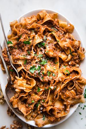 Walnut Vegan Bolognese with lentils with pasta on a plater with a serving spoon