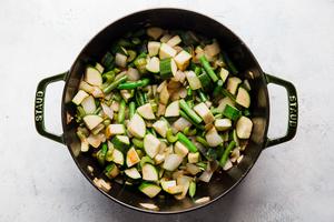 chopped onions, celery, garlic, zucchini and green beans being cooked in a large pot for vegetable soup