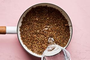 water and lentils being added to a pot to cook until tender
